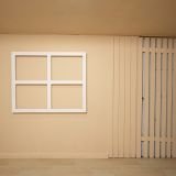 Prop de ventana blanca minimalista sobre pared beige en estudio creativo.